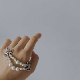 Designer Westwood double layered pearl studded diamond bow high-end bracelet exudes a feminine sweet minimalist charm