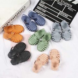 Sandaler barns nya mode PVC Summer Solid Color Metal Buckle Boys and Girls Baby Casual Flat Day Hollow Sandalsl240510