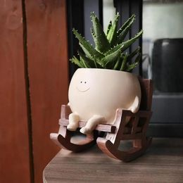 A type of plant pot for indoor plants. Adorable resin flower head plant sitting on a rocking chair with a juicy pot with drainage holes 240524