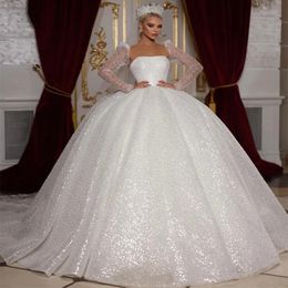 Atemberaubendes 2024 Weißes, glamouröses, glitzerndes Ballkleid-Hochzeitskleid mit trägerlosen Knöpfen am Ausschnitt und luxuriösen Perlenapplikationen mit langen Ärmeln und Prinzessin-Brautkleid