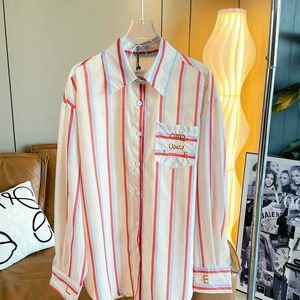 Mäns avslappnade skjortor 23 år ny Luo Jia Lowe färgglad rand vertikalt mönster Midlängd broderad skjorta solskyddsmedel lös och mångsidig kvinnodesigner skjortor