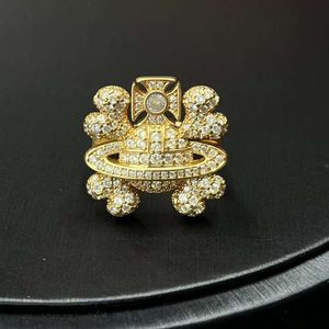 Designerin VivieneWestwoods Ring Die Kaiserinwitwe des Mittelalters öffnet ihren Mund voller Diamantringe Vivienne, ein leicht luxuriös vergoldeter Totenkopf mit einem Satur