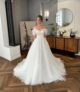 Romantico abito da sposa a trapezio con spalle scoperte e maniche a sbuffo. Eleganti applicazioni di perline Abiti da sposa in pizzo ricamati con tulle scivoloso e pizzo voluminoso