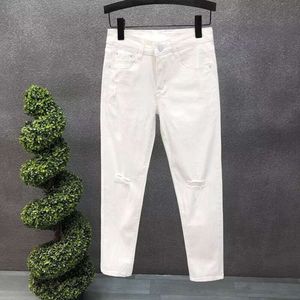 Mäns vita nödställda jeans, våren och sommaren smal passande små benbyxor, koreansk version trendig elastisk casual mode beskurna byxor