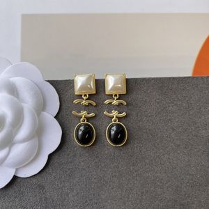 Cor principal combinação de preto, ouro e branco com brincos de pingente, acessórios de joias de charme de mulher madura
