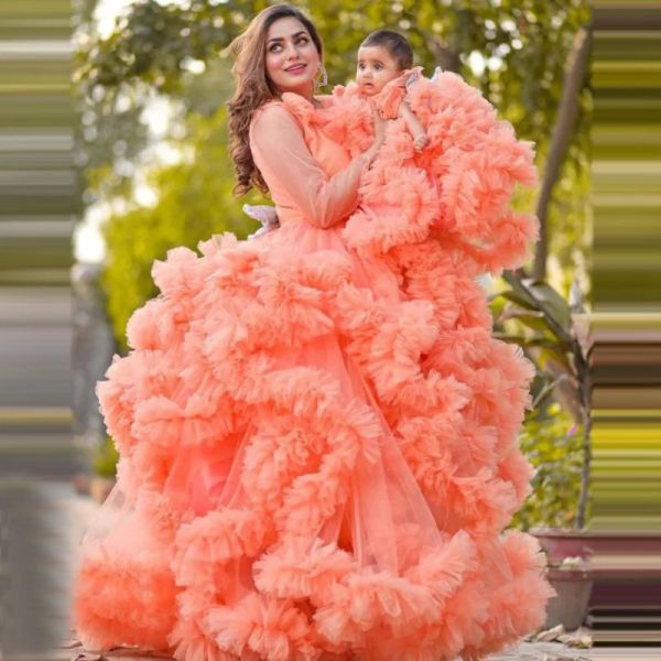 Abiti di lusso in corallo per madre e figlia in tulle con maniche lunghe e volant extra gonfi. Look familiare per baby shower, servizio fotografico, abito da ballo