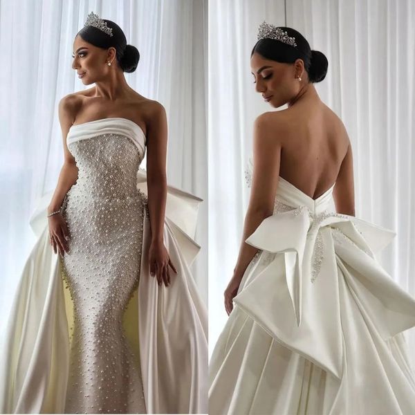 Stunningbride 2024 Abiti da sposa a sirena senza spalline sexy moda bianca Africa Perle Abiti da sposa senza schienale Custom Made Abito con grande fiocco