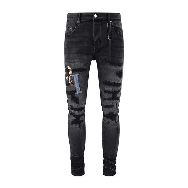 Jeans neri slim fit elastici con foro strappato in pelle patchwork con lettera stracciata di marca alla moda di nuova strada per uomo