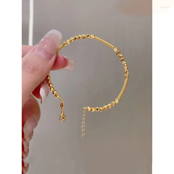 Armreif aus goldenem Farbprodukt mit Federabstand und springendem Ball. Armband Nischendesign für Damen, kompakt