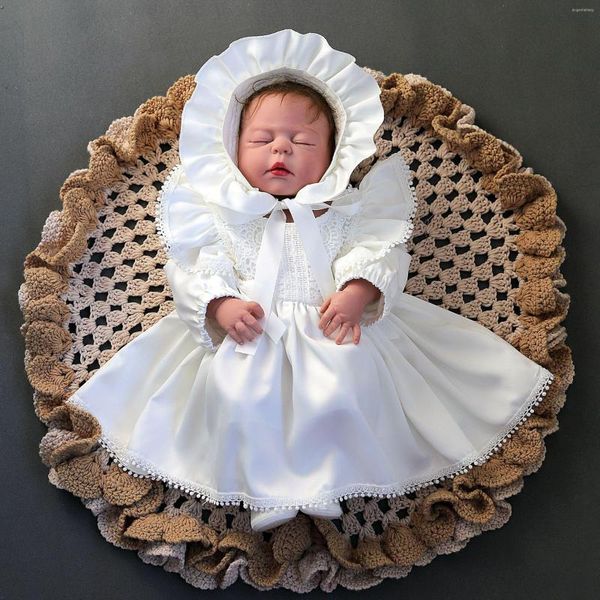La ragazza veste il bambino per il battesimo con il cappello Elegante abito da ragazza formale in pizzo a maniche lunghe in stile corte