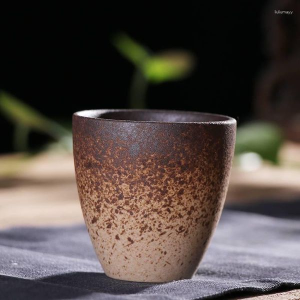 Tassen, Untertassen, die Tee rund um den Herd kochen, brennende Lampen und Brennholz bauen, lila Sand, grobe Keramik