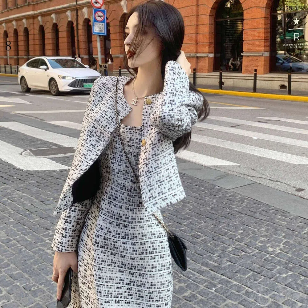 Chic woman in a patterned dress with a matching jacket, showcasing stylish wedding guest outfits on a city street.