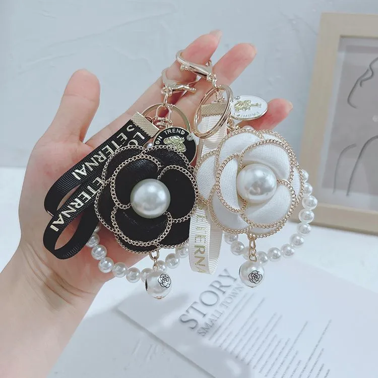 Korean version of pearl string camellia key chain petal personality bag key chain hanging decoration high appearance level car couple key chain