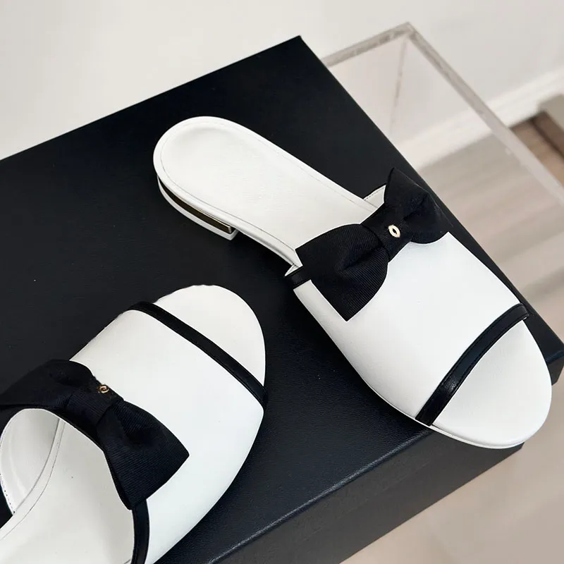 Kvinnors slip på sandaler låga klackar tofflor designer glider lammskinn bowknot grosgrain mules slingbacks flip flops utomhus strandsko retro svart vit casual sko