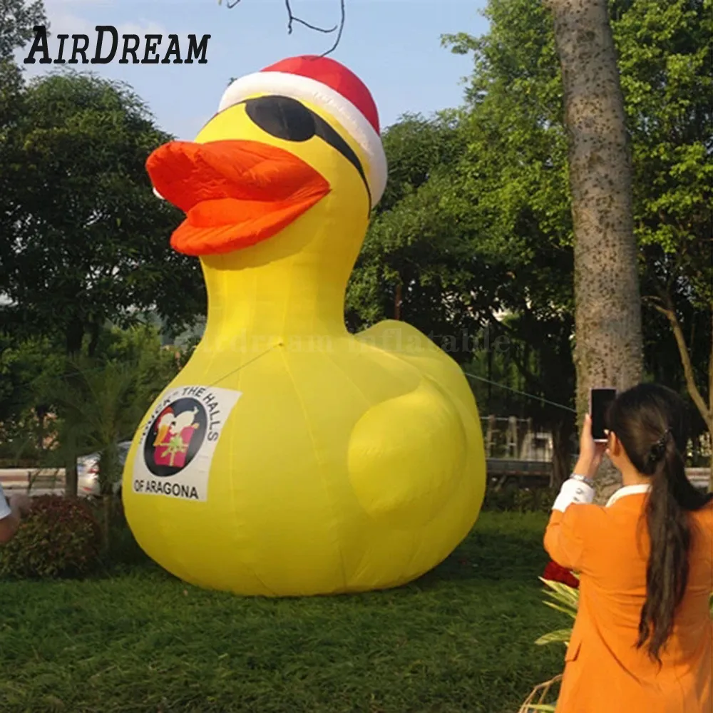 wholesale Réplique de canard gonflable jaune mignon 8 mH (26 pieds) avec ventilateur avec un chapeau rouge Modèle de mascotte animale soufflée par air pour la décoration de parc et de piscine