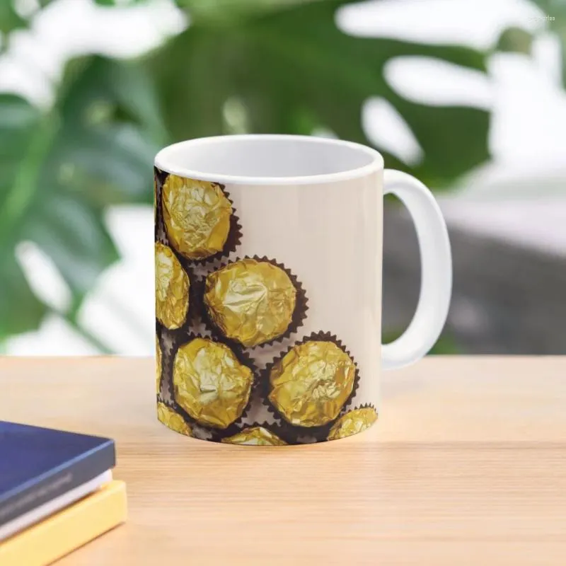 Tasses formant une forme de triangle à partir de bonbons au chocolat dorés de qualité supérieure isolés sur une tasse à café fond rose