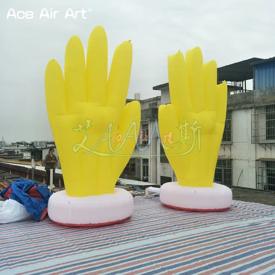 Une paire de mains gonflables jaunes géantes avec un modèle de paume soufflé à l'air de base pour la décoration extérieure ou un événement
