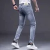 Jeans para hombres Jeans de diseñador Jeans de moda para hombres con personalidad Versión coreana Slim Fit Parche versátil y desgastado Pantalones de mendigo azul claro Insignia de patrón