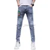 Jeans para hombres Jeans de diseñador Jeans de moda para hombres con personalidad Versión coreana Slim Fit Parche versátil y desgastado Pantalones de mendigo azul claro Insignia de patrón