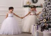 2015 Тюль платья для девочек-цветочниц Прозрачные аппликации из бисера Пушистые рождественские бальные платья для свадьбы Замочная скважина на шнуровке с бантами Прекрасный заказ M8204710