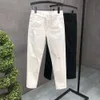Mäns vita nödställda jeans, våren och sommaren smal passande små benbyxor, koreansk version trendig elastisk casual mode beskurna byxor