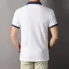 デザイナーは新しい夏のスタイルを推奨しました！ユニークで人目を引く刺繍パターンを備えたピュアコットンのターンダウンカラーポロシャツは、男性のスタイルを示しています