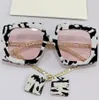 Óculos de sol femininos 0722s moda clássica de cor preta e branca com moldura de lente rosa de lente de metal templo com personalidade pendente1053341