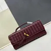 A bolsa noturna mais quente e elegante é uma bolsa de embreagem longa que é de couro e vem com uma alça, possui uma textura metálica e um fechamento de botão