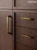 O armário de latão antigo lida com os botões de gaveta.