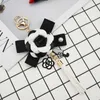 Ключевые кольца знаменитые бренд Keyring Black White Leather Camellia Camellia Camellia Camellia CwareChain Женские модные цветочные цепочки Llaveros Flore Bag Charms 240412