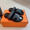 Talltor Chypre Sandal Designer Sliders Flop Flops Platta sandaler för strandkomfort kalvskinn Läder naturlig mocka getskinn i brunt och svart för kvinnor och män