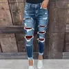 As calças jeans femininas elásticas de jeans lavadas com pés pequenos e quadris apertados ainda são mulheres.Rasgado