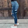 As calças jeans femininas elásticas de jeans lavadas com pés pequenos e quadris apertados ainda são mulheres.Rasgado