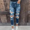 As calças jeans femininas elásticas de jeans lavadas com pés pequenos e quadris apertados ainda são mulheres.Rasgado