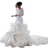 2024 Vestidos de novia de sirena de lujo Cuello transparente Manga larga Ilusión Volantes Botón con gradas Volver Capilla Tren Tallas grandes Vestidos de novia personalizados