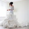 2024 Vestidos de novia de sirena de lujo Cuello transparente Manga larga Ilusión Volantes Botón con gradas Volver Capilla Tren Tallas grandes Vestidos de novia personalizados