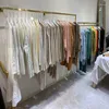Haczyki stojak wyświetlacza wysokiej jakości jasnozłoty sklep z odzieżą ze stali nierdzewnej jest zawieszony na kombinacji tytanowej półki ściennej