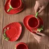 カップソーサー素敵なスタイルのイチゴは、ガラス張りのかわいいコーヒーカップとソーサーセットセラミックティーカップソーサーの下で手描きです。