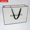 Cadeau cadeau 100x logo personnalisé imprimé vêtements au détail cadre noir sacs à provisions blancs sac de transport avec poignée de ruban pour vêtements