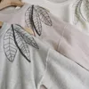 女性用セーターセーターセーター丸い首のソリッドカラーカシミアオフショルダー刺繍ビーズチェーン秋のルーズプロフィールニットレディートップ