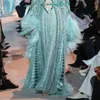 Vestindo um vestido de noite verde com lantejoulas e penas no último lançamento da marca Zuhair Murad em 2023