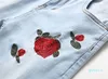 Les jeans masculins déchirés avec des broderies fleurs de fleurs rose brodées stress stress maigre