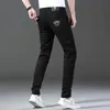 Mäns jeans designer designer nya vår sommarmän jean ren svart vit tvåfärgad bomull hög elastisk liten fot smal passande koreansk medusa broderade byxor