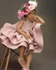 2023 Blush Pink Flower Girls Abiti per matrimoni Halter senza maniche in pizzo Appliques Perline di cristallo Lunghezza al ginocchio corto Tiered Bow Compleanno Bambini Ragazza Abiti da spettacolo