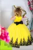 2023 Nieuwe gele tule kanten kansengirljurken voor bruiloftsploeg nek mouwloze zwarte applique vleugel boog lange meisjes optocht jurken