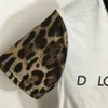 Modemarke mit Buchstabendruck und Leopardenmuster, schlanke, kurze Frau