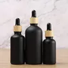 Bouteille de parfum d'huile essentielle liquide en verre noir mat avec compte-gouttes de réactif et bouteilles d'emballage de bouchon de grain de bois