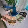 2023 Womens Shoes Summer Ny platt botten Metallknapp tofflor Kvinnor bär mode casual koreanska joker sandaler och tofflor.