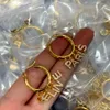 Nowe zaprojektowane triomfe łukowe kryształowe kolczyki z mosiądzu ze złotymi błyszczącymi kobietami Ear Hoops Designer Jewelry CE9000