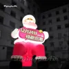 Festlicher riesiger aufblasbarer Weihnachtsmann-Modell-Weihnachtsmann, der ein Schild für Weihnachtswerbeveranstaltung hält